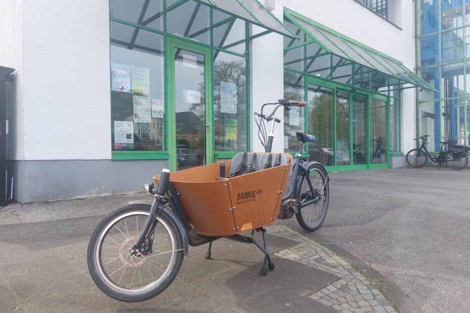 Ein Lastenrad in holländischer Optik mit hölzerner Ladebox, in der eine Sitzbank für Kinder montiert ist