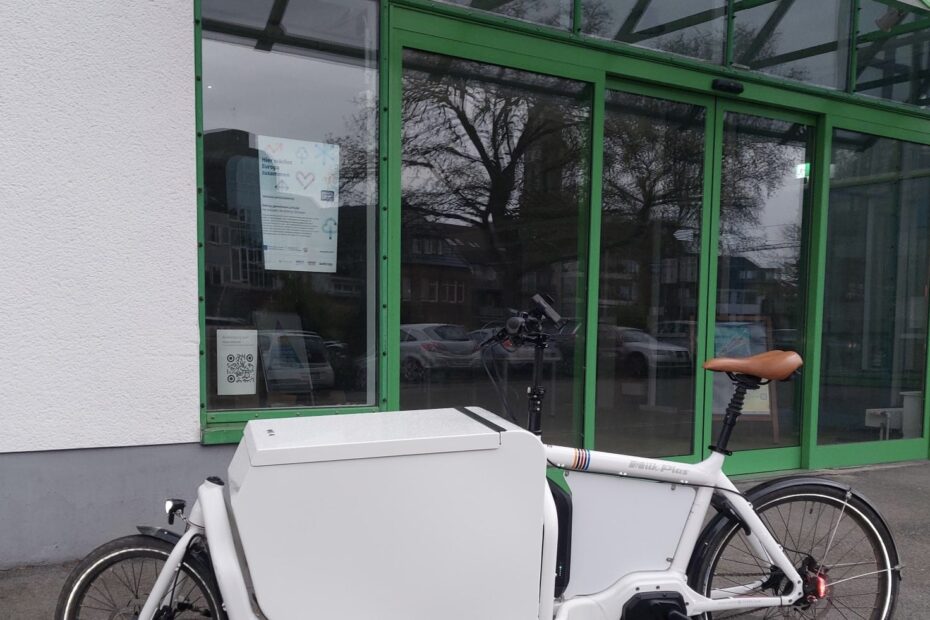Ein ganz in weiß gehaltenes Lastenrad mit großer, rundum verschlossener Alubox auf der Ladefläche